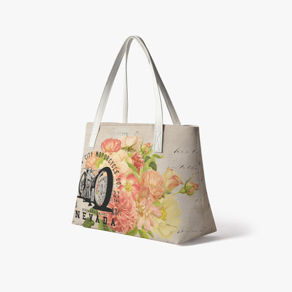 VCMCo. Born and Raised in Nevada vegan leather tote bag in dramatic studio spotlight — floral and vintage motorcycle graphic front and center on white background