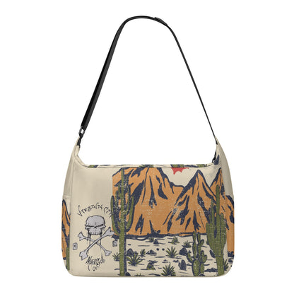VCMCo. Skull & Crossbones Desert Messenger Bag — back view - tan canvas with Virginia City Motorcycle Co. skull logo and desert mountain scene print, black adjustable shoulder strap