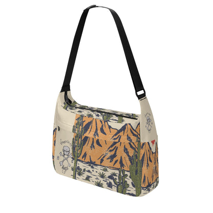 VCMCo. Skull & Crossbones Desert Messenger Bag —side view -  tan canvas with Virginia City Motorcycle Co. skull logo and desert mountain scene print, black adjustable shoulder strap