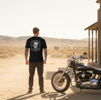 Man wearing VCMCo. Toxic Victorian skull motorcycle t-shirt in black, standing next to a motorcycle in a Nevada desert town setting — original skull biker apparel